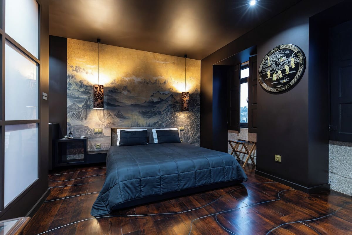 Un dormitorio moderno con una cama grande, un mural en la pared y una obra de arte circular.