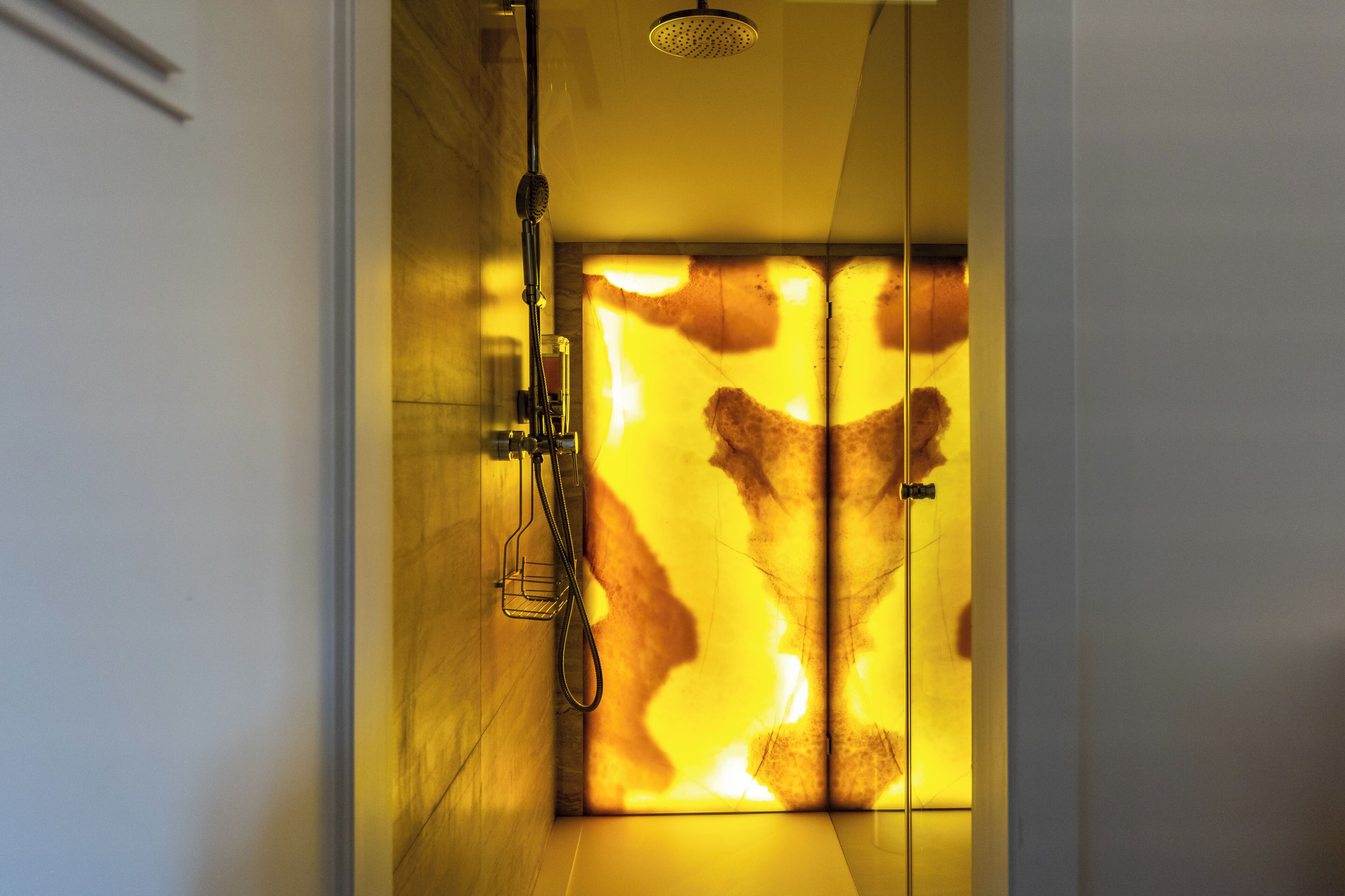 Ein modernes Badezimmer mit Duschkabine aus Glas, Handbrause und sichtbarer Bedienfeld für die Dusche.