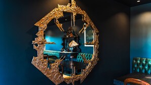 Ein Zimmer mit einem großen, runden Wandkunstwerk aus Metall, einem gepolsterten grünen Sofa und einem Holztisch mit Glasplatte.