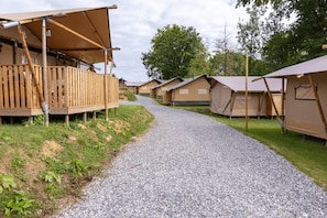 A gravel path leading to a row of wooden cabins with attached porches, surrounded by greenery. - Arden Parks Signy L'Abbaye (Signy-l'Abbaye)
