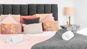 Una cama bien hecha con una variedad de almohadas y una toalla blanca enrollada.