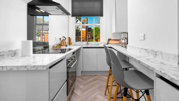 Een moderne keuken met een centraal eiland, roestvrijstalen apparatuur en uitzicht op buiten.