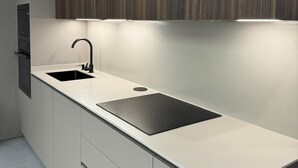 A modern kitchen with a sleek countertop, two sinks, and a built-in oven.
