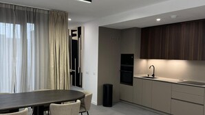 A modern kitchen with a dark countertop, beige cabinets, and a built-in oven.