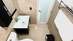 Un baño con inodoro blanco, un lavabo con espejo y un perchero para toallas.