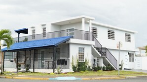 Un edificio blanco con techo azul, un balcón y una escalera.