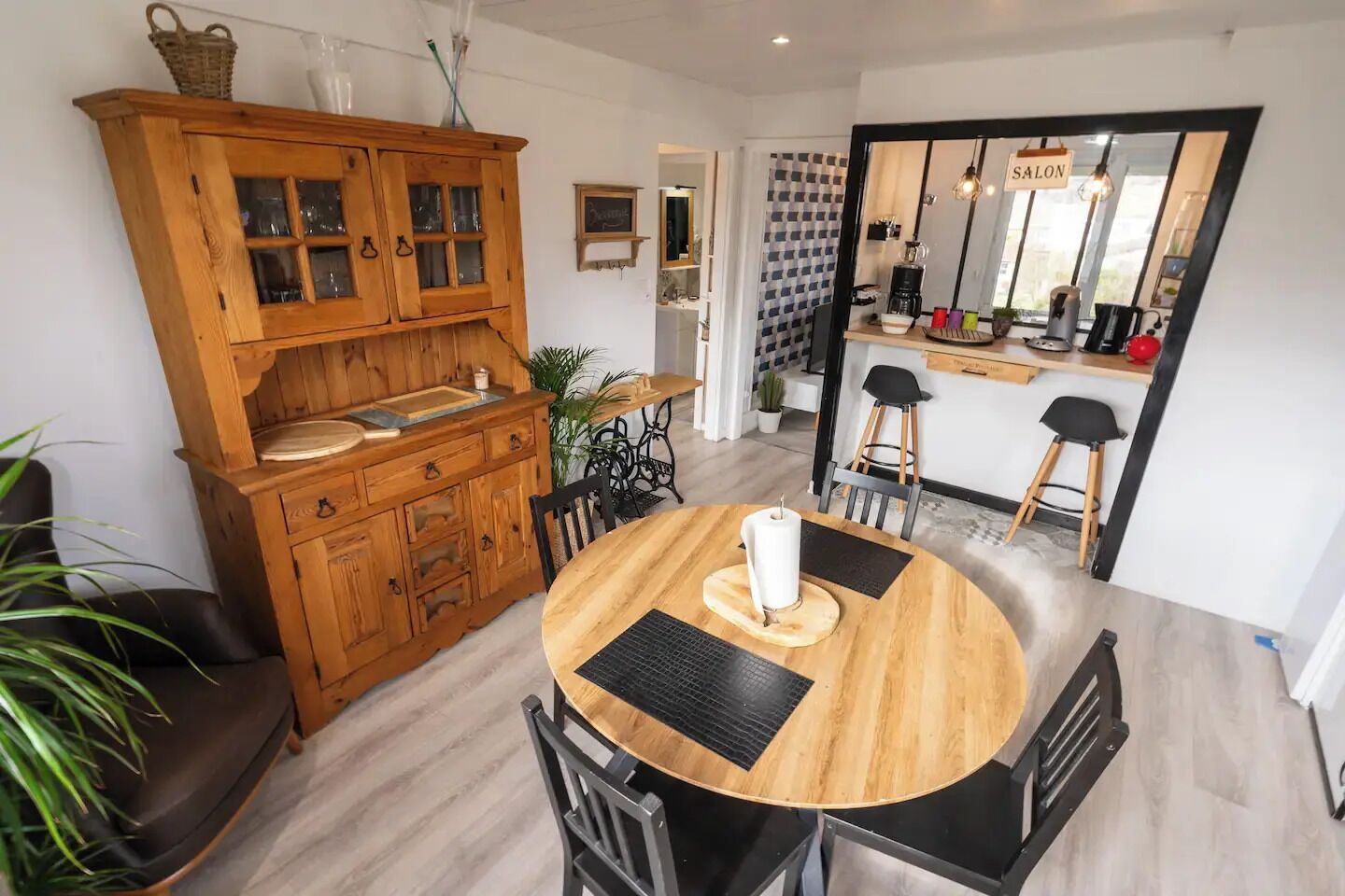 A modern kitchen with wooden cabinetry, a round dining table, and black chairs.