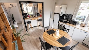 A modern kitchen with a round wooden table, black chairs, and a built-in oven. - Entire apartment - Saint-Dié-des-Vosges, France  (Saint-Dié-des-Vosges)