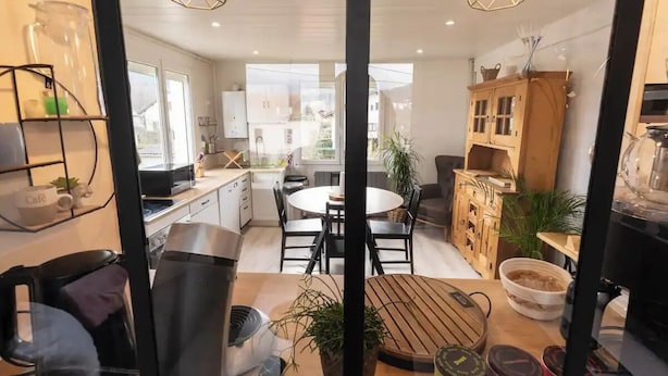 A modern kitchen with a dining area, wooden cabinets, and a large window providing natural light. - Entire apartment - Saint-Dié-des-Vosges, France  (Saint-Dié-des-Vosges)