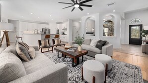 Ein modernes Wohnzimmer mit einer großen Couch, einem Couchtisch und einem Deckenventilator.