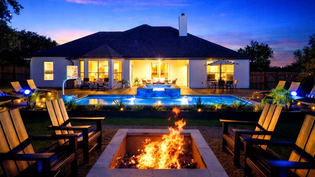 Ein Haus mit Swimmingpool, Sitzgelegenheit im Freien und einem Feuerkorb.