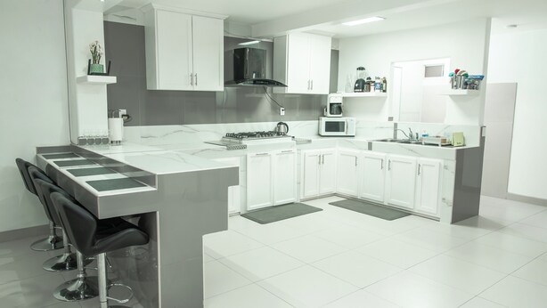 Una cocina moderna con una isla central, muebles blancos y electrodomésticos de acero inoxidable.