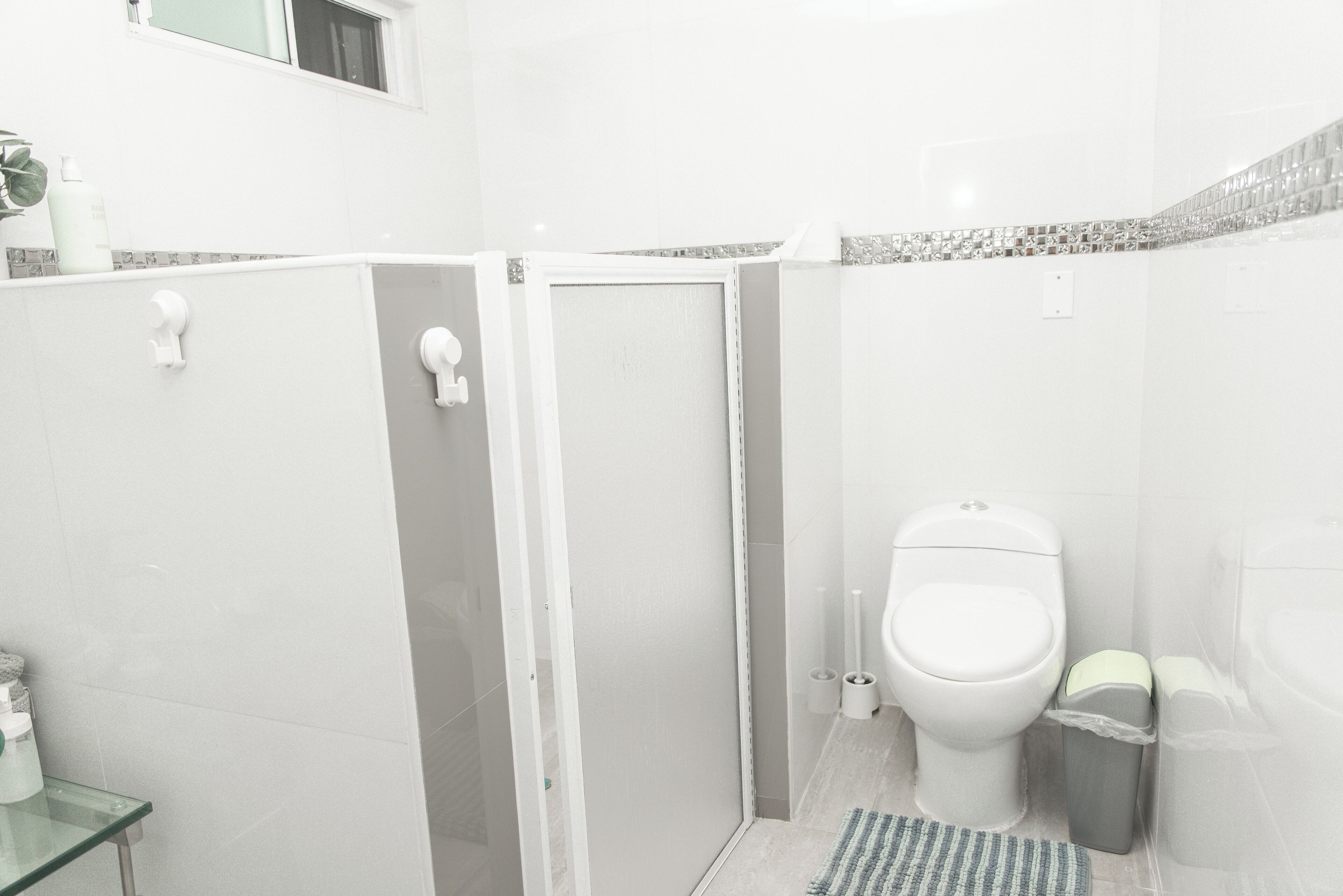 A bathroom with a shower, toilet, and glass-enclosed sink.