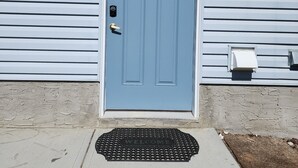Una puerta azul con un ventanal encima, un buzón y un felpudo.