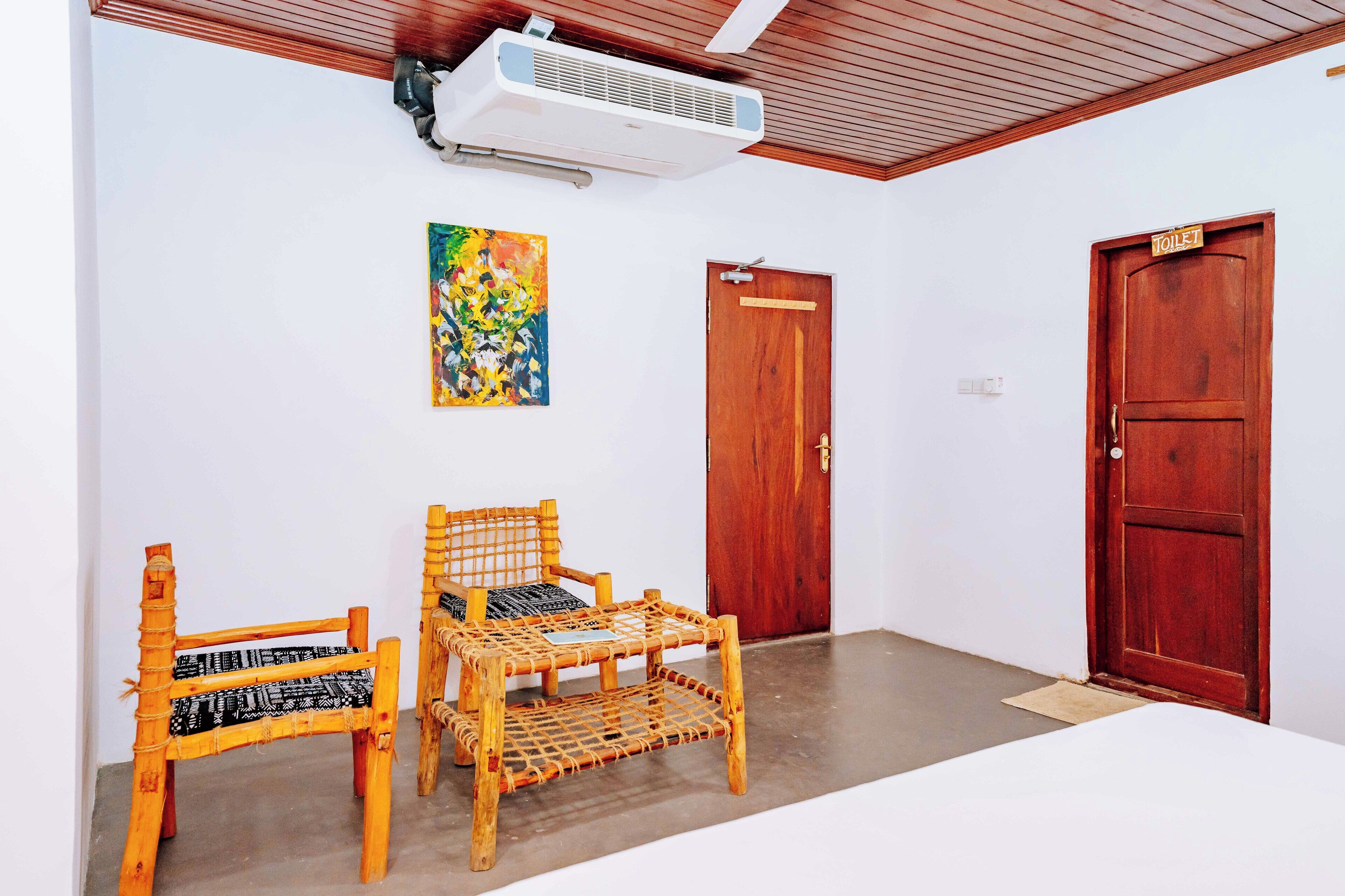 A room with two wicker chairs, a wooden door, and an air conditioning unit on the ceiling.