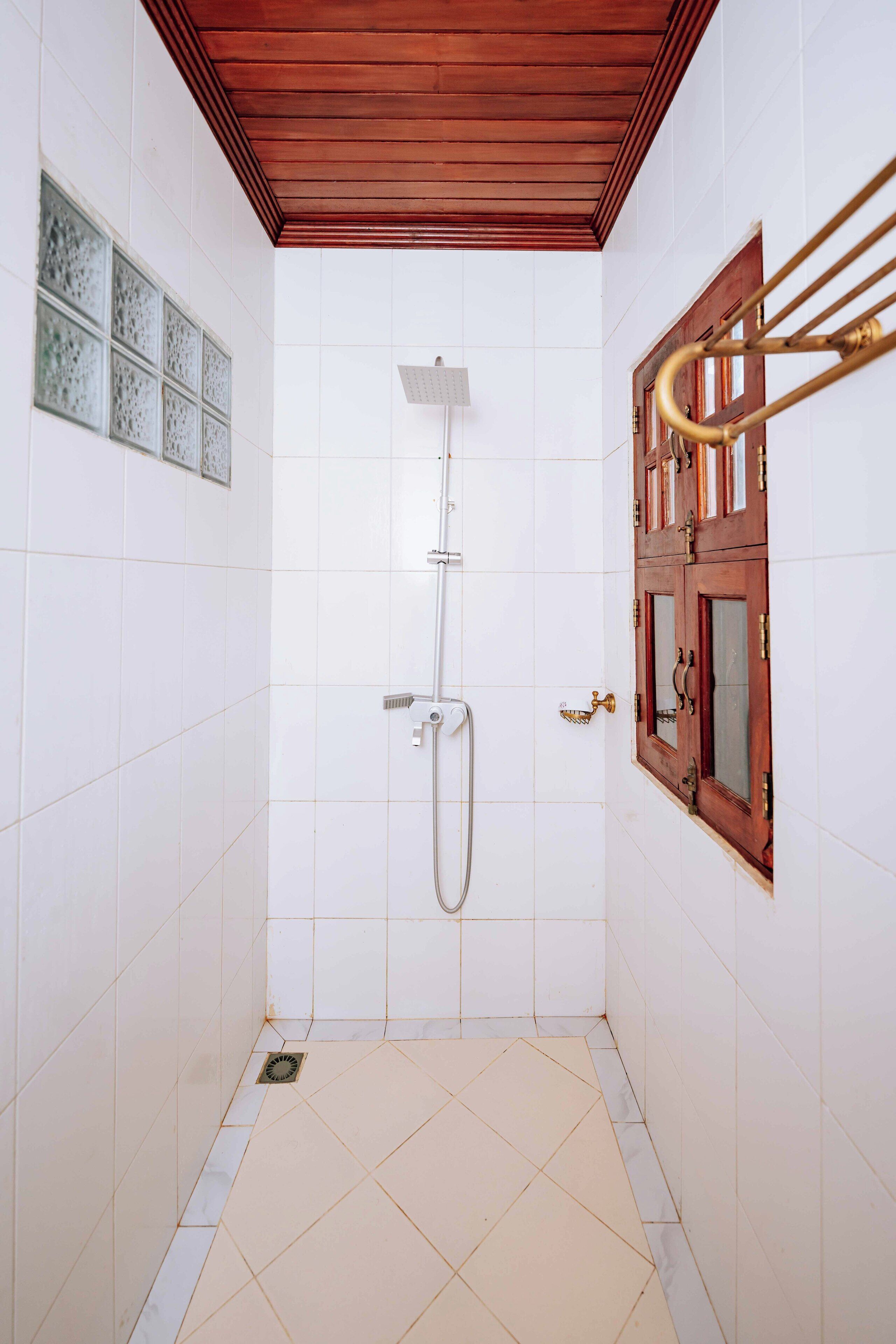 Un baño pequeño con revestimiento de azulejos, techo de madera y puerta de madera con paneles de vidrio.