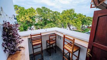 A balcony with three wooden chairs and a potted plant.