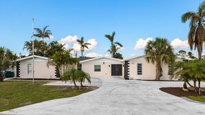 A residential area with three houses, a clear driveway, and palm trees.