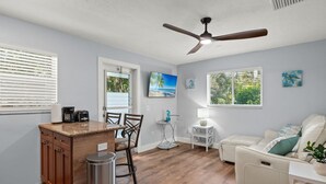 A compact living space with a kitchen area, a dining table, a white sofa, and a ceiling fan.