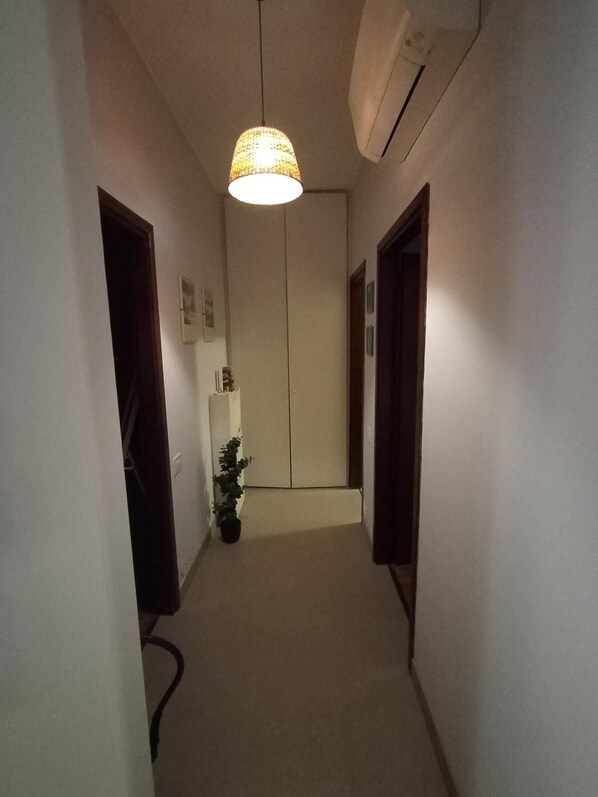 A narrow hallway with a hanging light fixture, a potted plant, and a door at the end. - Viadanteunovigevano - 200 meters from Piazza Ducale (Vigevano)