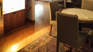 Una sala de estar con una mesa de comedor, sillas, una araña y una estantería.