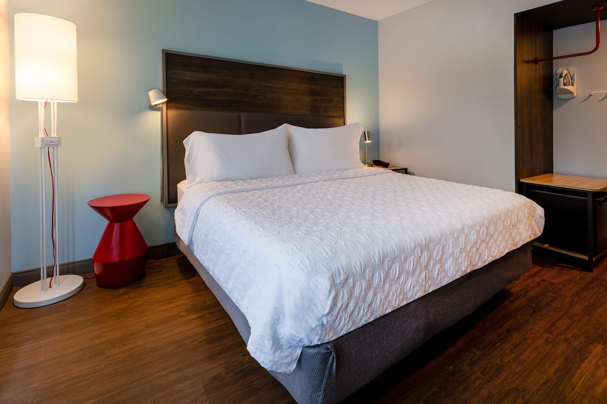 A neatly made bed with white bedding in a modern hotel room.