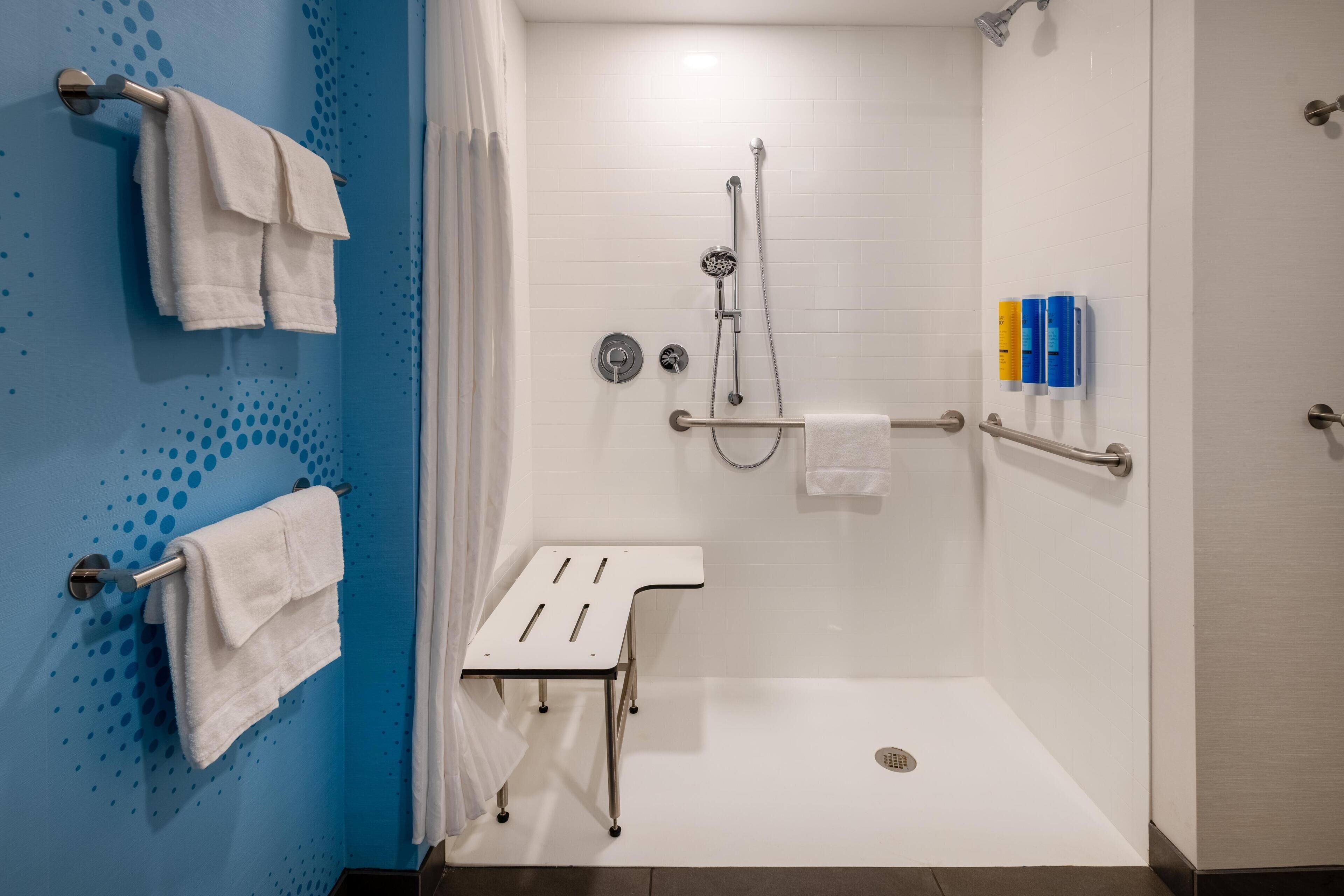 A modern shower area with a white floor, a white towel rack, and a white towel on the rack.