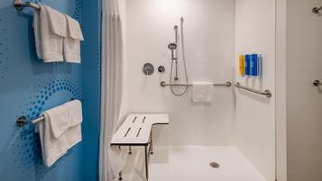 A modern shower area with a white floor, a white towel rack, and a white towel on the rack.
