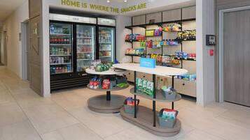 A snack kiosk with a sign reading 'HOME IS WHERE THE SNACKS ARE' and a variety of snacks displayed on shelves.