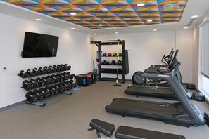 Ein Fitnessstudio mit Laufbändern, Kurzhanteln und einer Hantelbank.