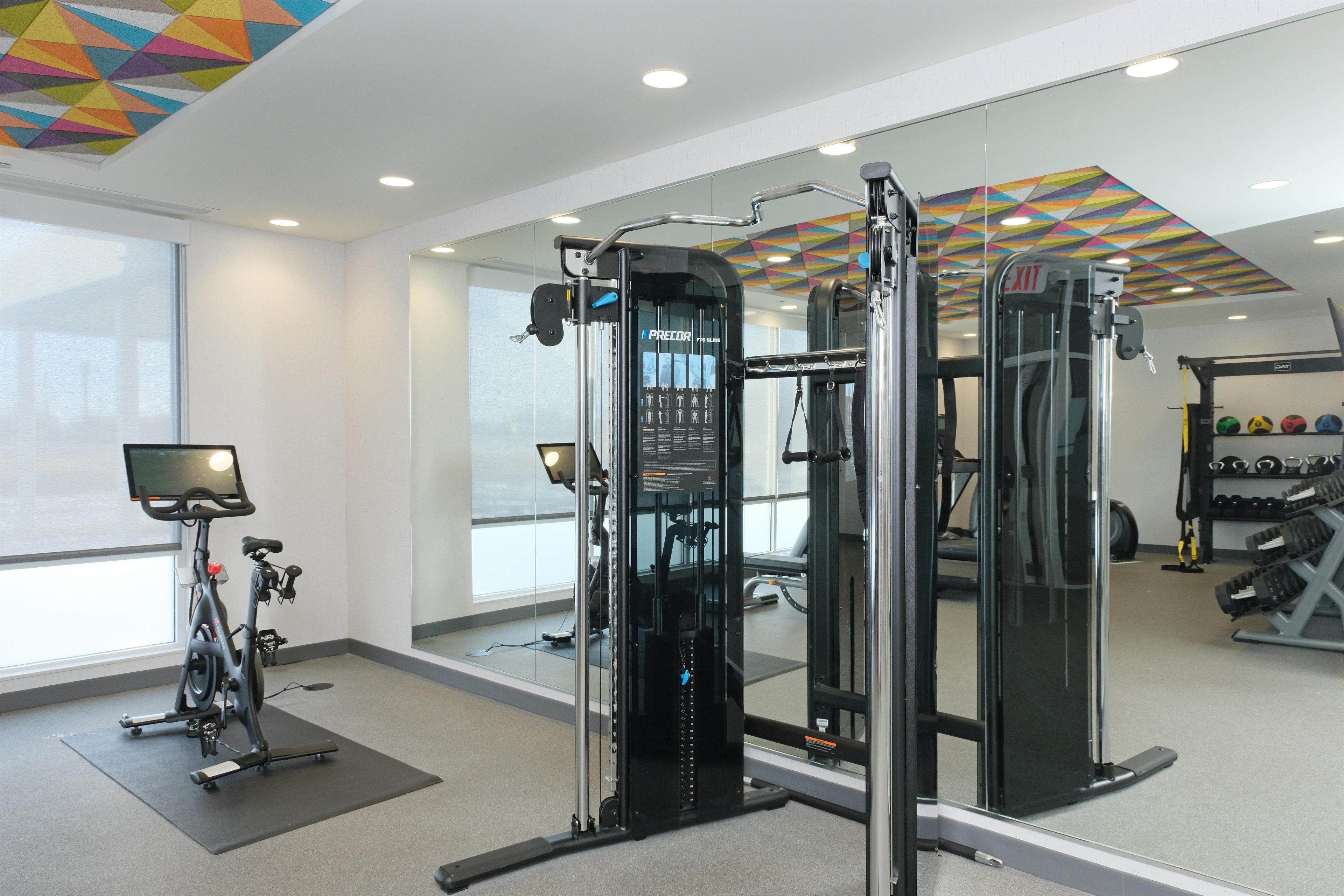 A gym with exercise equipment, a bike, and a mirror reflecting the interior.
