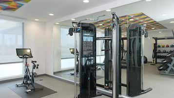 A gym with exercise equipment, a bike, and a mirror reflecting the interior.