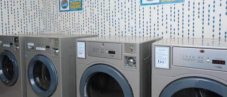 A row of front-loading washing machines in a commercial setting.