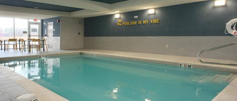 An indoor swimming pool with a sign on the wall that reads "POOLSIDE IS MY VIBE".