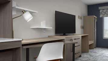 Ett modernt sovrum med skrivbord, stol, TV och garderob.