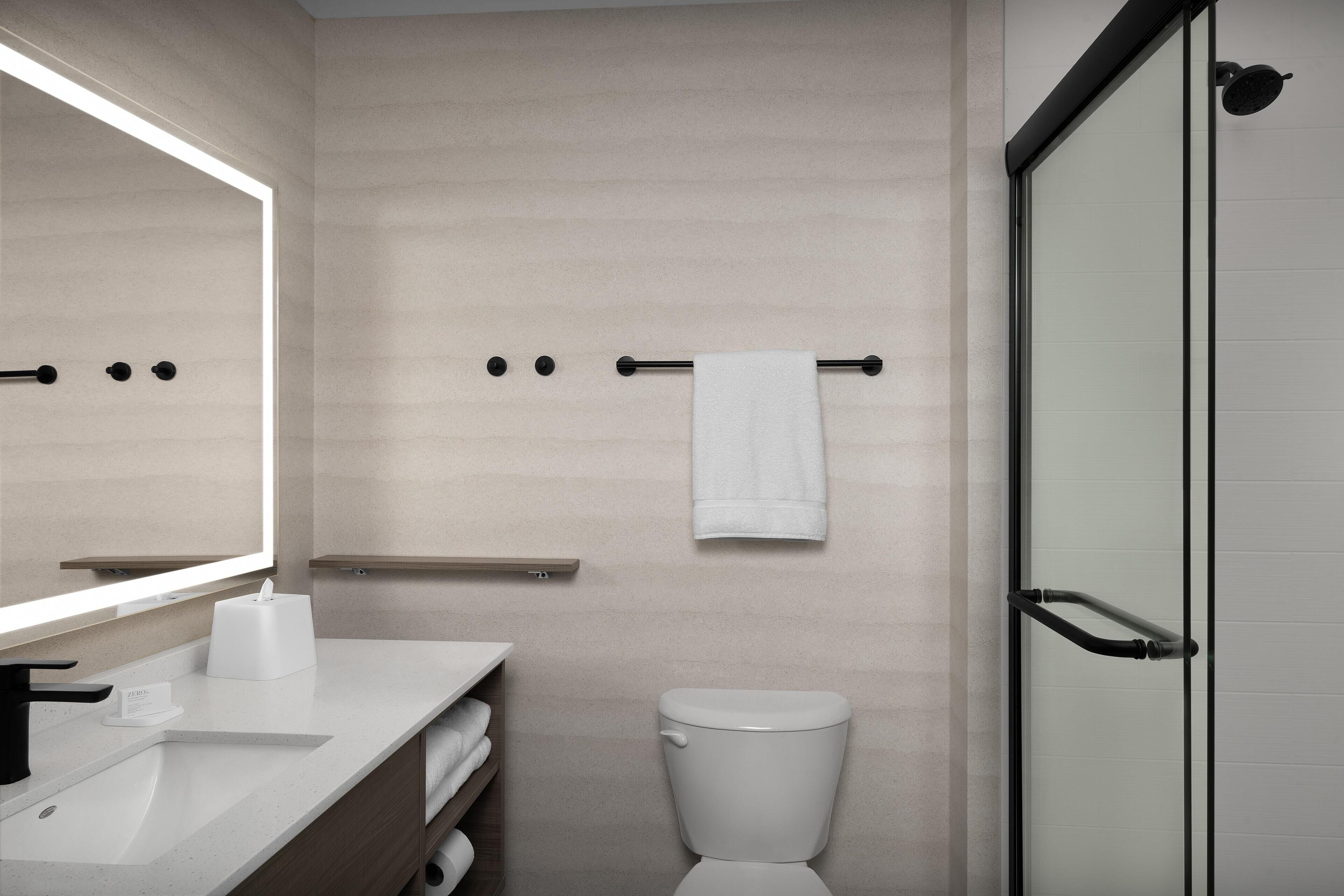 A modern bathroom with a toilet, sink, and a glass shower enclosure.