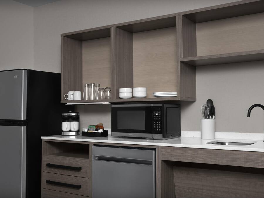 A modern kitchen with a stainless steel refrigerator, a black microwave, and a built-in dishwasher.