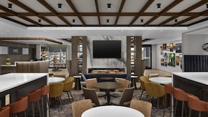 Een moderne lounge met een open haard, bar en zitplaatsen.