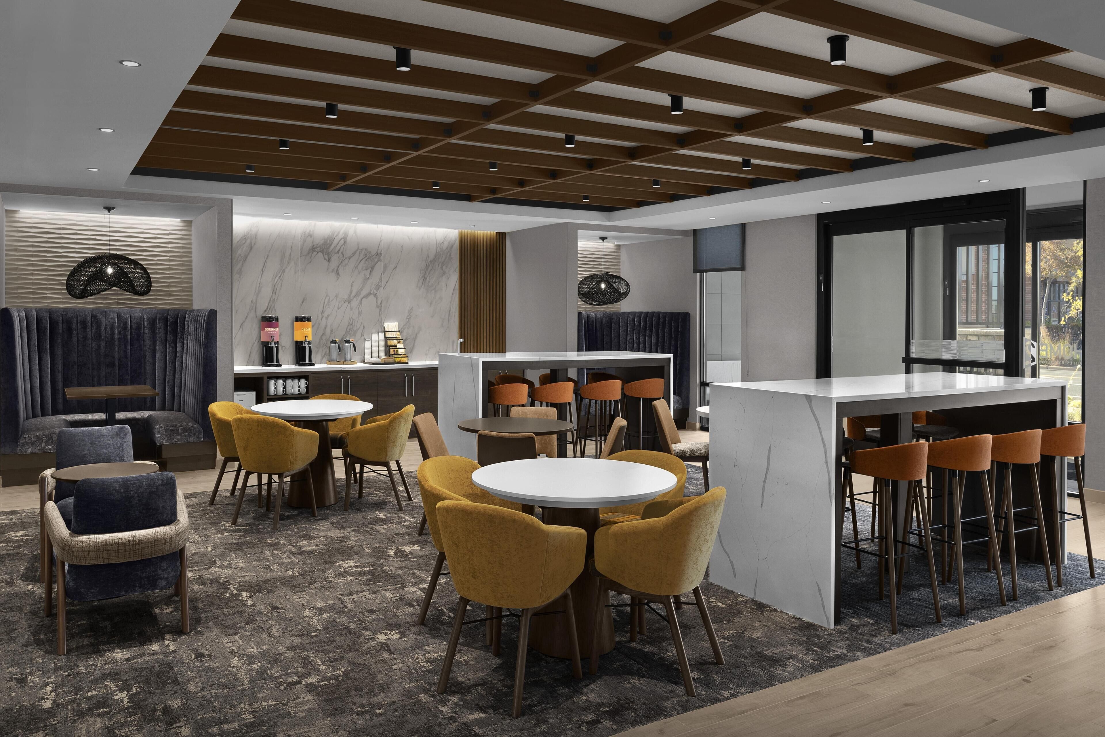 A modern interior with a bar area, round dining tables, and comfortable seating.