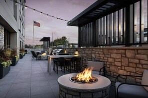 Un espace extérieur aménagé en terrasse, avec un foyer en pierre, des sièges et un barbecue.