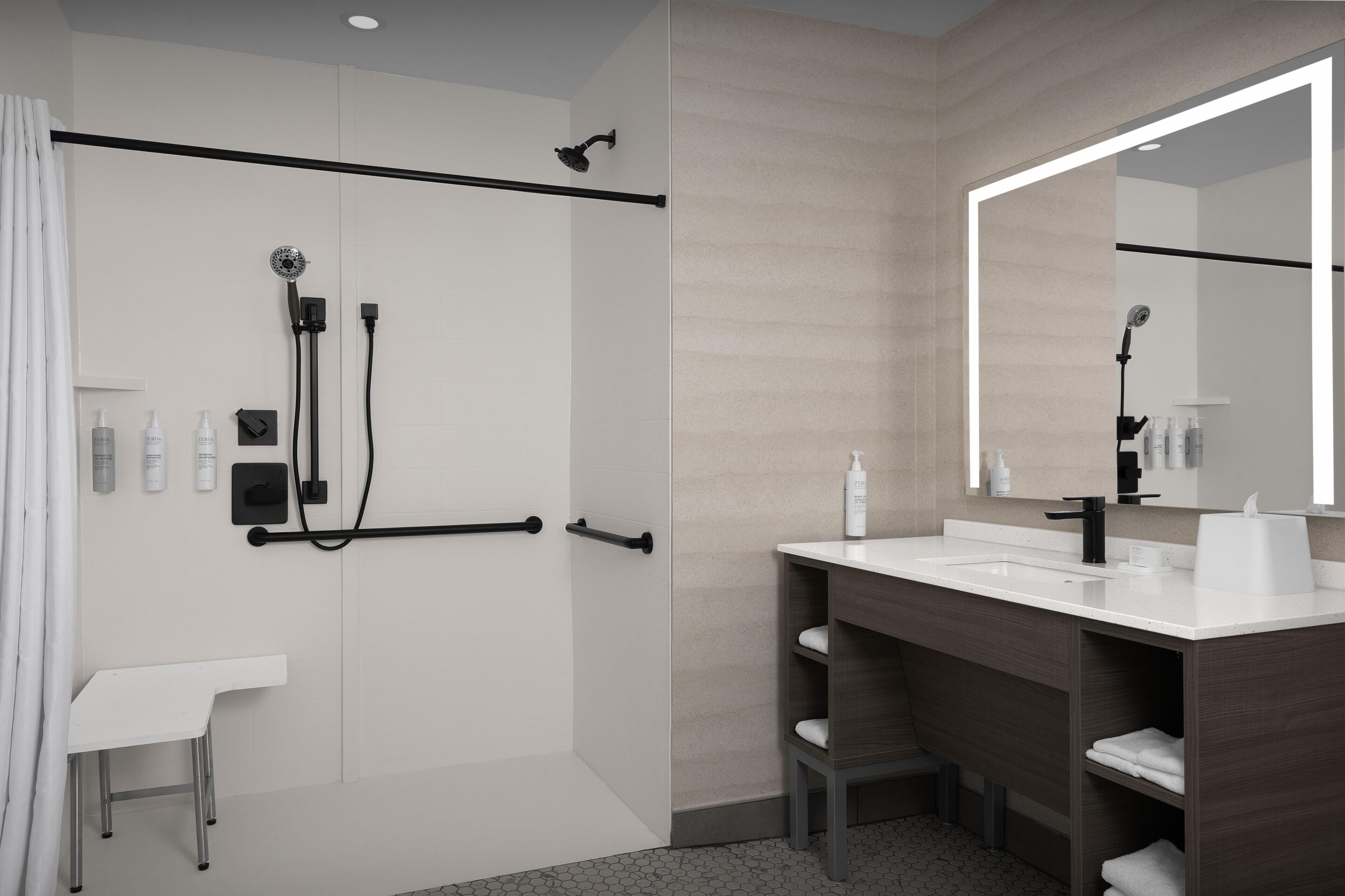 Un baño moderno con ducha, tocador y un espejo grande.