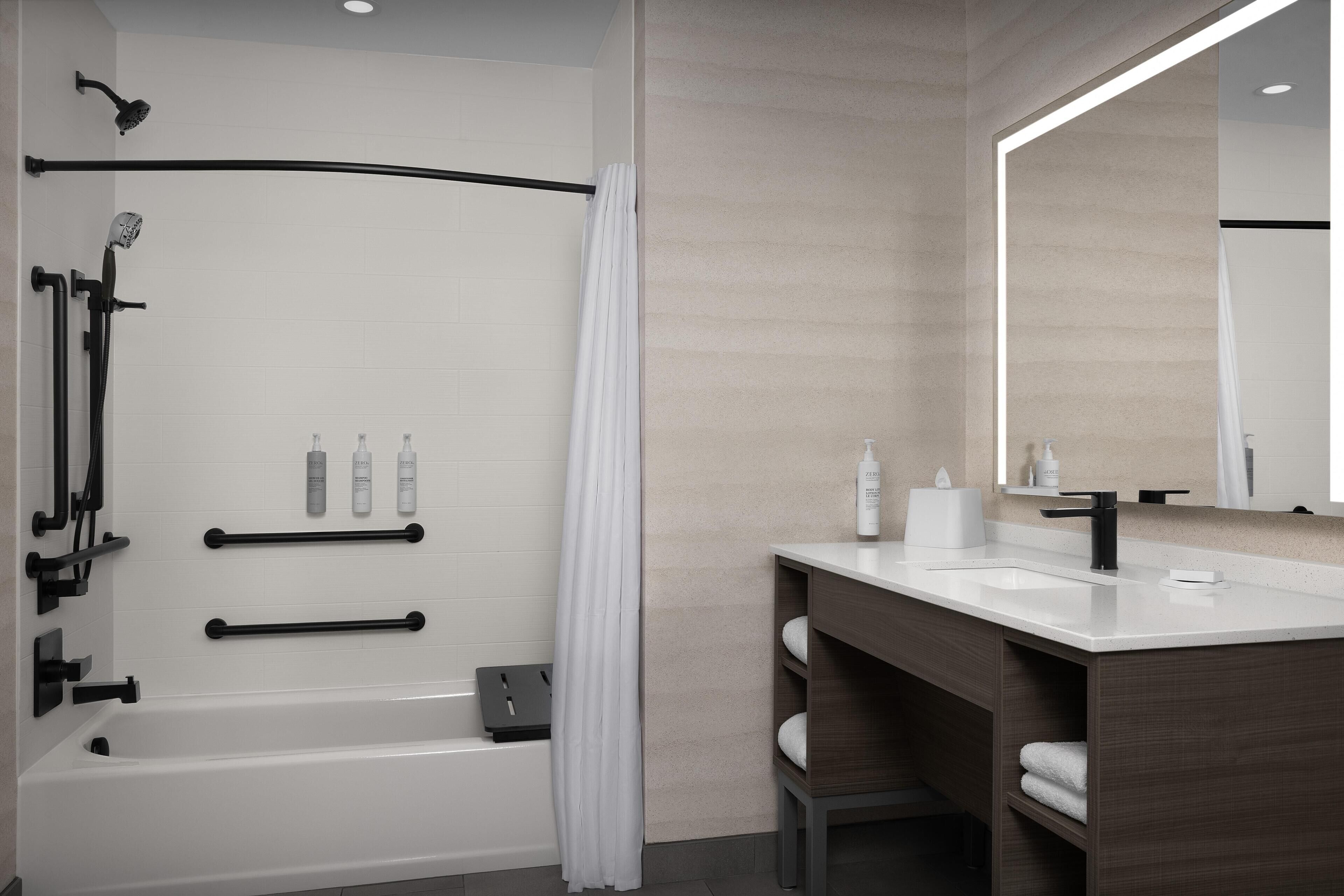 Une salle de bain moderne équipée d’une baignoire, d’une douche et d’un meuble-lavabo avec un miroir.