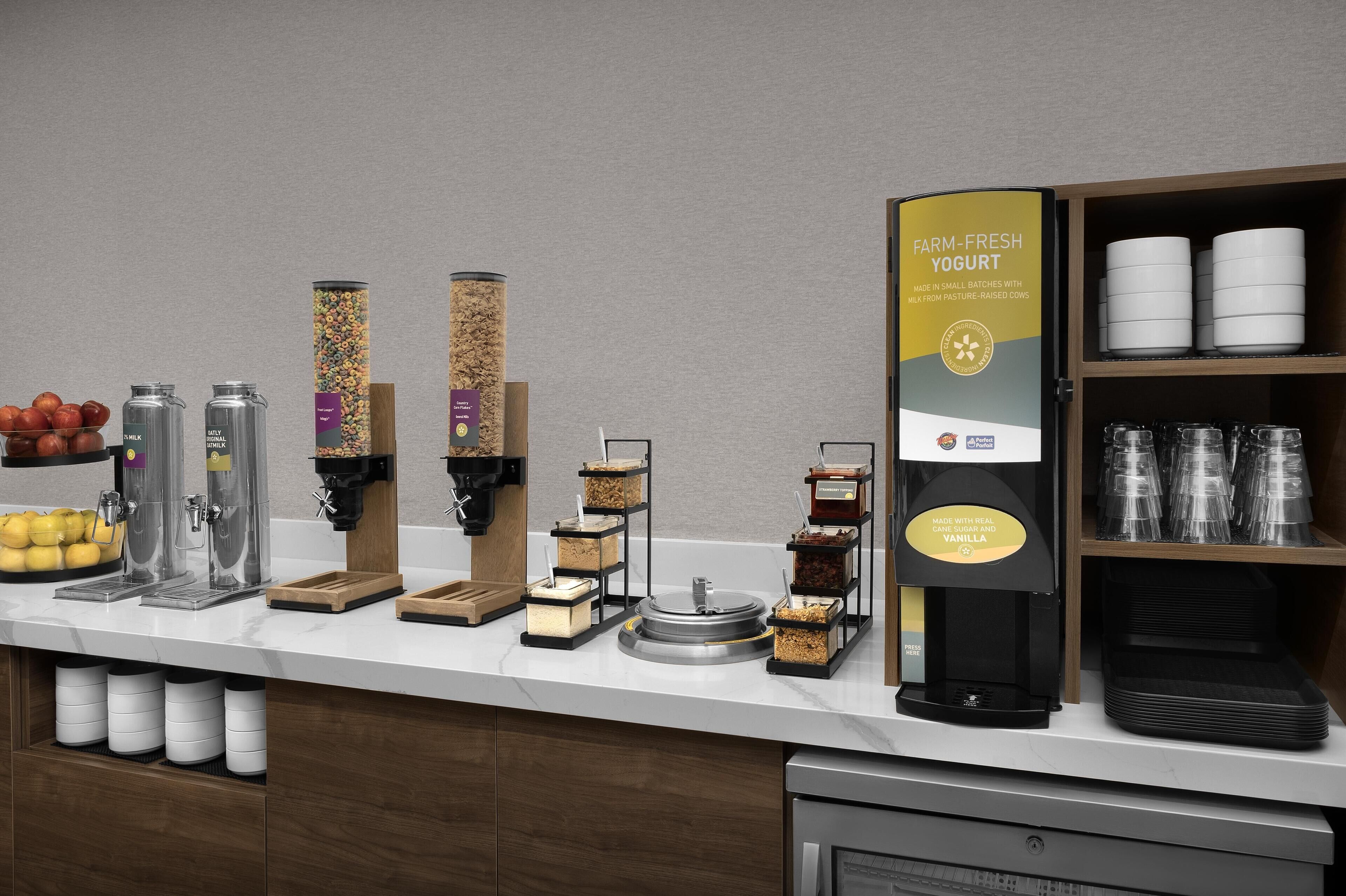 A breakfast bar with various food and drink dispensers, including yogurt, cereal, and coffee options.