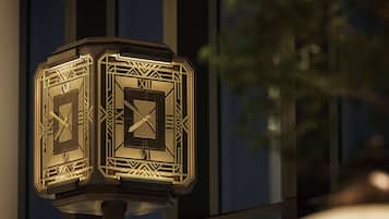 A decorative clock with Roman numerals and geometric patterns, mounted on a post.