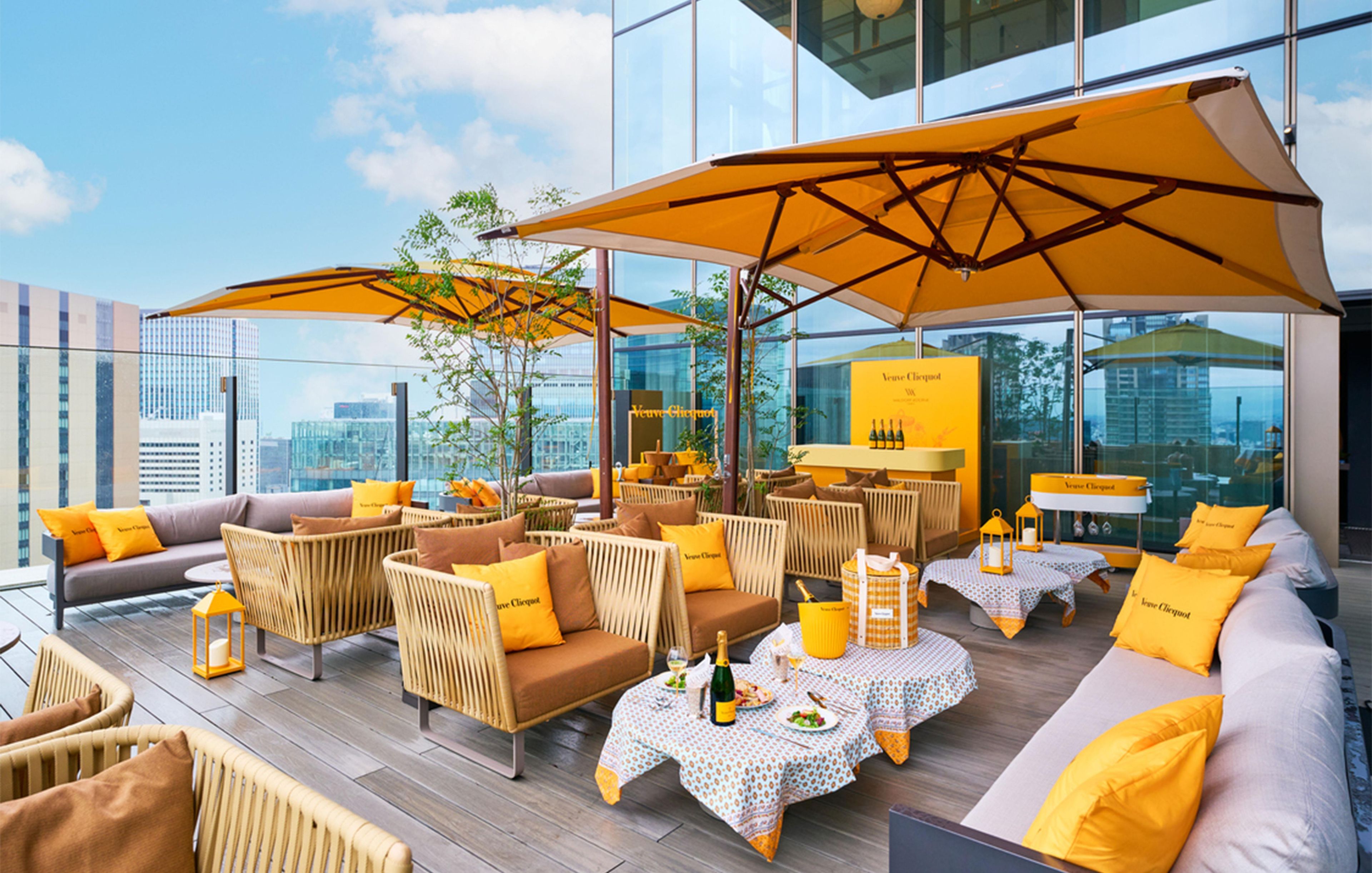 Tagterrasse med udendørs siddepladser, parasoller og udsigt over byen.