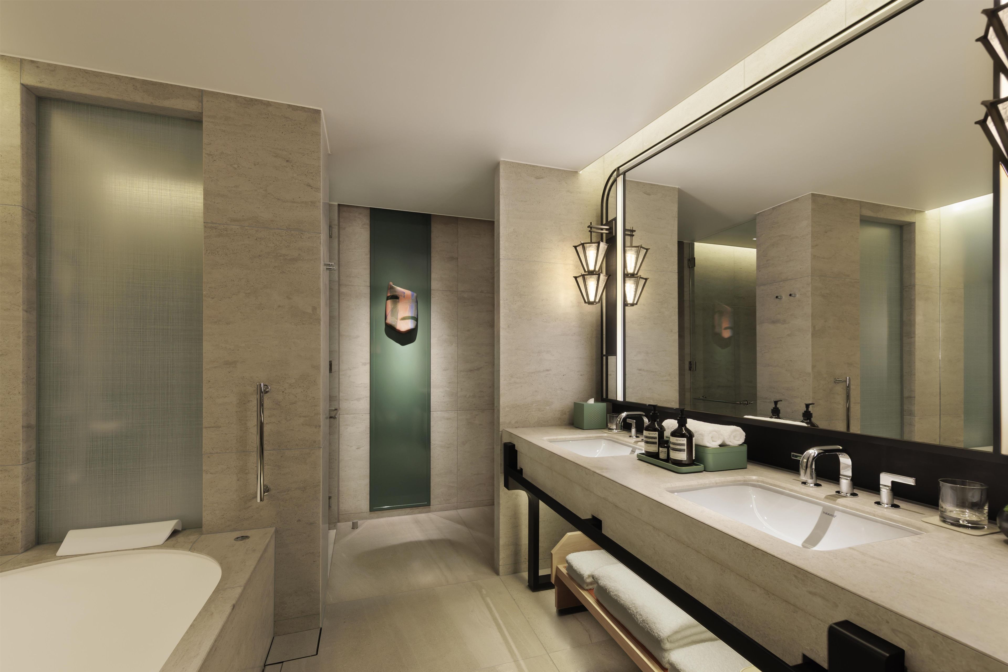 Un baño moderno con bañera, dos lavamanos, un espejo grande y ducha.