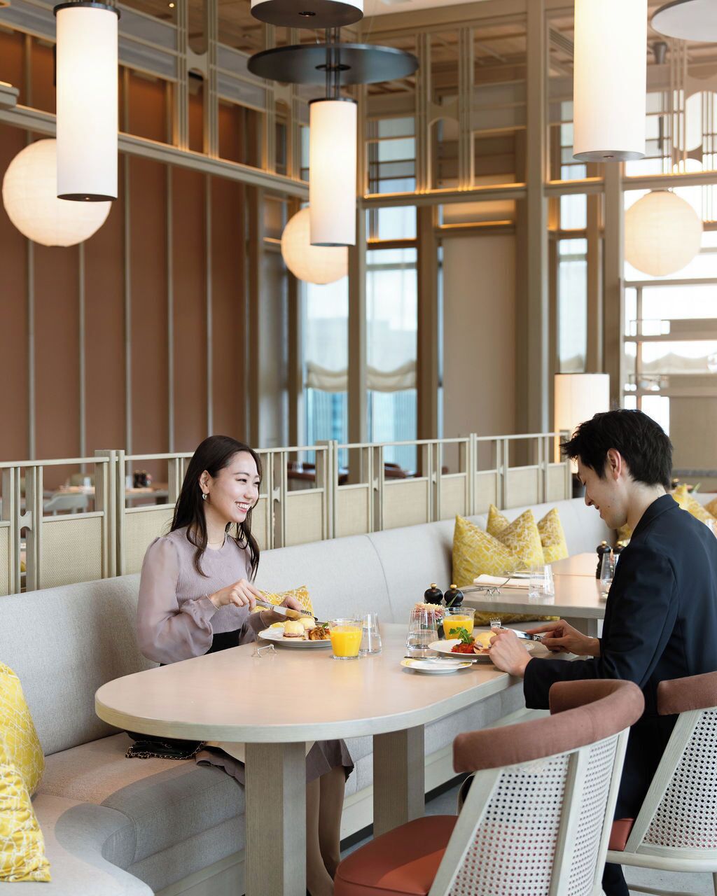 Un comedor moderno con una mesa redonda, asientos acolchados e iluminación colgante.