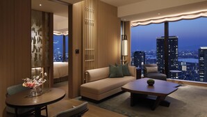A modern hotel room with a city view, a sofa, a coffee table, and a dining area. - Waldorf Astoria Osaka (Osaka)