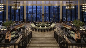 A spacious bar area with multiple seating options, a central bar counter, and large windows offering a city view. - Waldorf Astoria Osaka (Osaka)