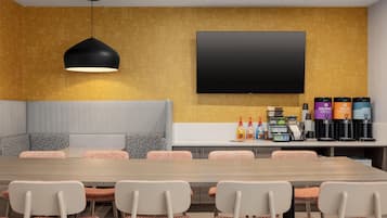 Une salle de réunion moderne équipée d’une longue table, de chaises, d’un canapé, d’un téléviseur à écran plat et d’un coin café.